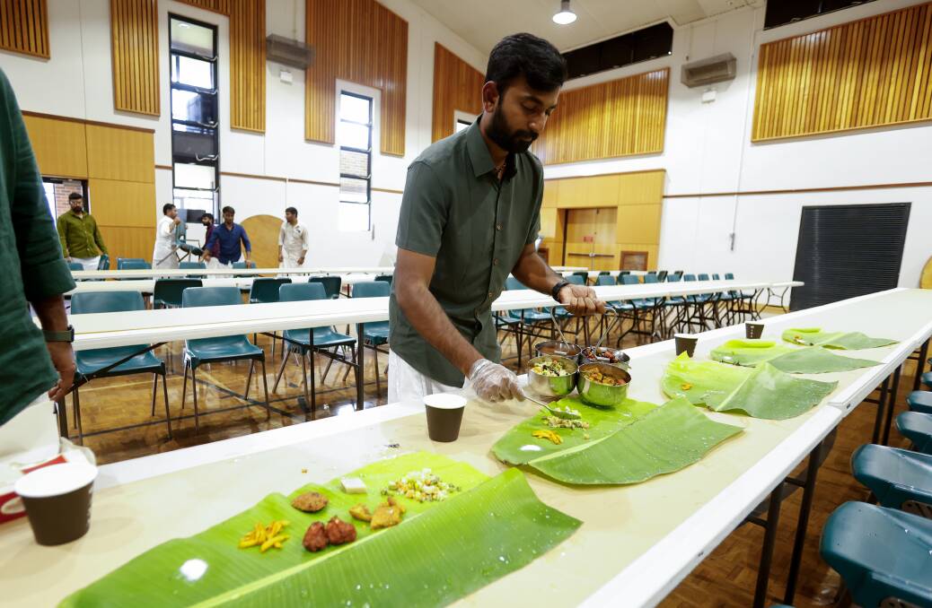 Harsha Muthu preparing the feast by placing traditional South Indian food, including pickled mango, onto banana leaves. Picture by Anna Warr