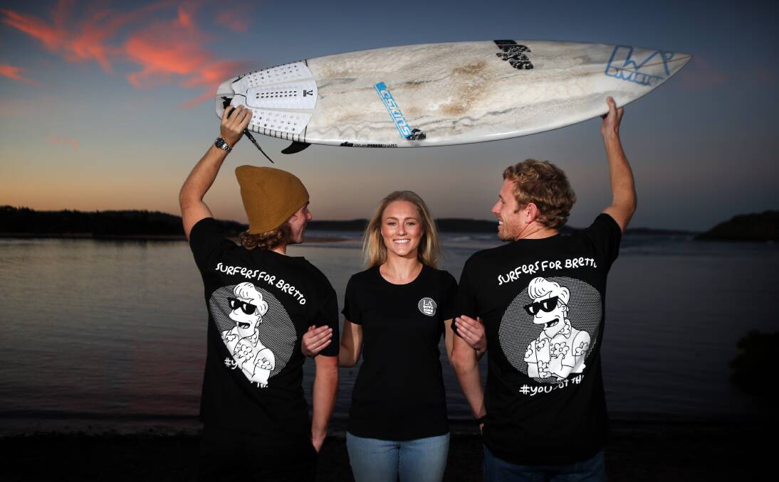 Raising funds: Holding the surfboard Brett Connellan was riding when attacked by a shark, Geoff Latimer, Agie Krowka and Joel Trist are working behind the scenes to aid their mate's recovery. Picture: Sylvia Liber.