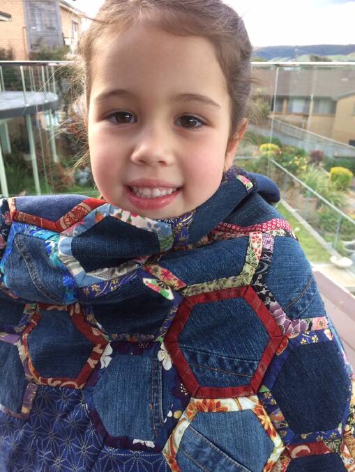 Sienna Woolley, 5, of Gerringong keeps warm wrapped in the denim quilt you could win in the raffle.