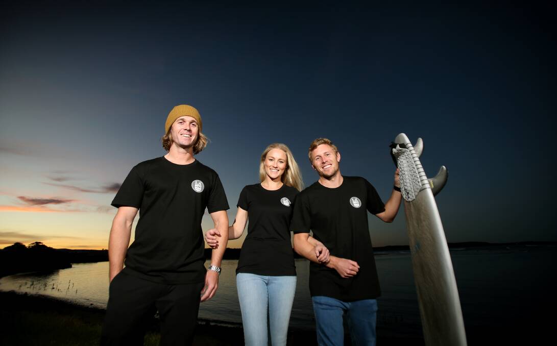 Raising funds: Holding the surfboard Brett Connellan was riding when attacked by a shark, Geoff Latimer, Agie Krowka and Joel Trist are working behind the scenes to aid their mate's recovery. Picture: Sylvia Liber.