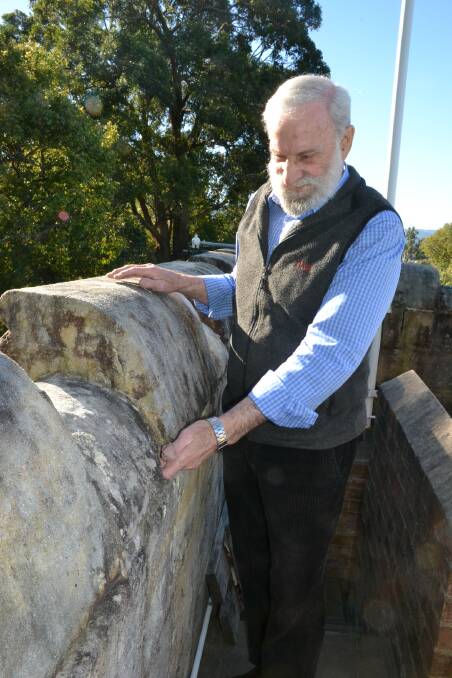 Nowra RSL Sub-Branch president Fred Dawson places his hand into one of the gaps where mortar has fallen out.

