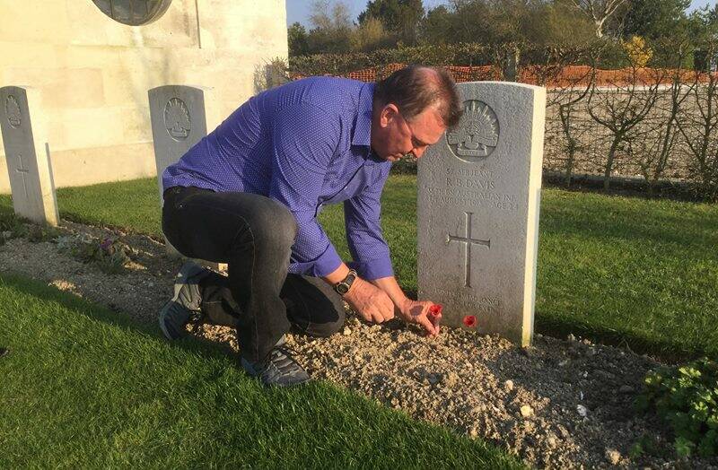 Rick Meehan lays a poppy to pay respect to Sergeant Ray Davis on behalf of George Wheatley, of Moruya.
