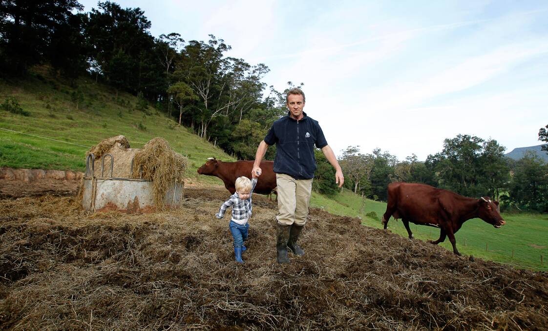 Jamberoo dairy farmer Steven Downes, 35, and his son Leo. Mr Downes runs his 120 cow operation by himself, works around 80 hours each week and has only had around 45 days off since 2010. Picture: Sylvia Liber