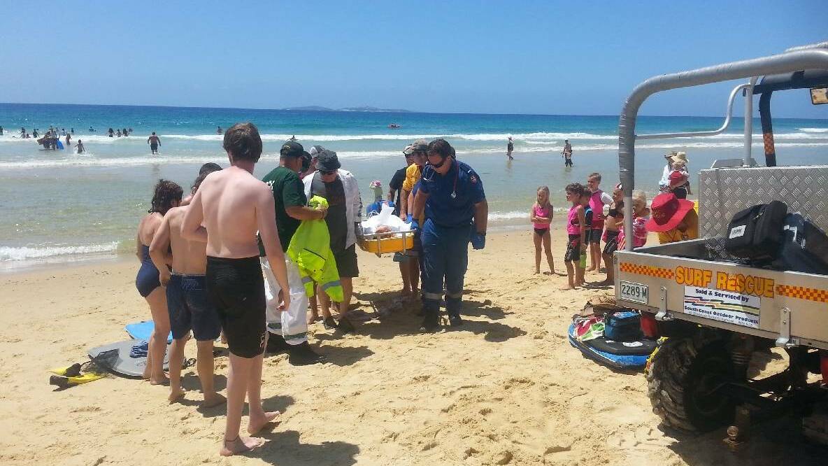 Ambulance paramedics, VRA rescue squad members and patrol members start to carry the stricken young woman up the Narooma surf beach back in 2014. 