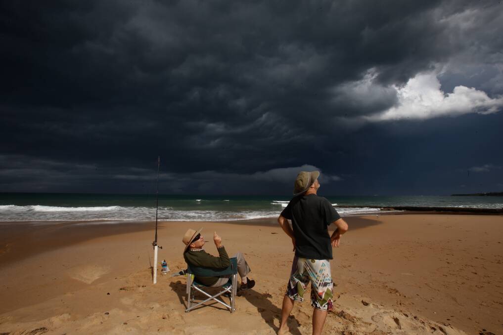 Bob Deadman and his son, Glen, watch a storm pass over Thirroul in February - a month many storm-related insurance claims were lodged. Picture: Adam McLean
