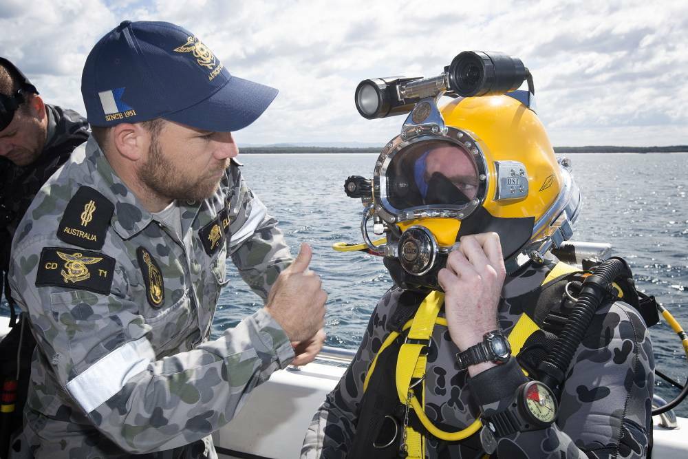 OK: Able Seaman Clearance Diver Luke Elliott prepares Able Seaman Clearance Diver Nathan Brooks to dive to the Firefly wreckage site to place a memorial plaque on the wreckage in Jervis Bay. Photo: Sarah Ebsworth
