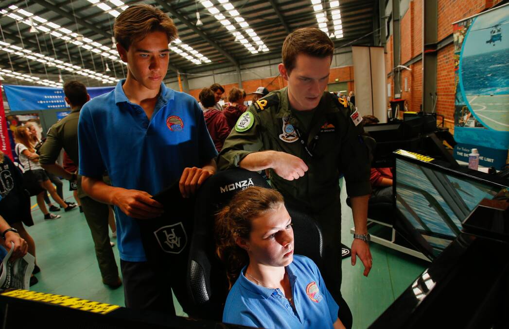 CAREERS: Bulli High Yr 10 students Zac Duczynski and Olivia Heathcote try out a flight simulator with Navy pilot Peter Brewster at the Careers Expo. Picture: Adam McLean
