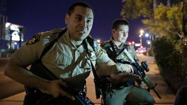 Police officers tell people to take cover after shootings in Las Vegas. Photo: John Locher
