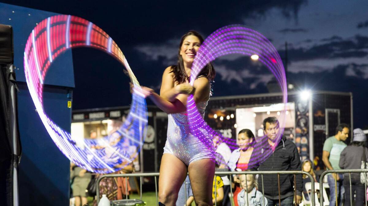 A woman performs with glow-in-the-dark hula hoops. 
