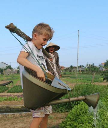 A 90-year-old farmer teaches children how to water the oldfashioned way. Photo: Jason Thompson