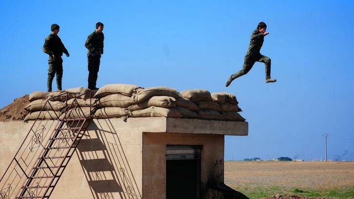 Three young YPG fighters prepare to leap from their lookout near the village of Tel Marouf, freed from the Islamic State two days before.  Photo: Fadi Yeni Turk