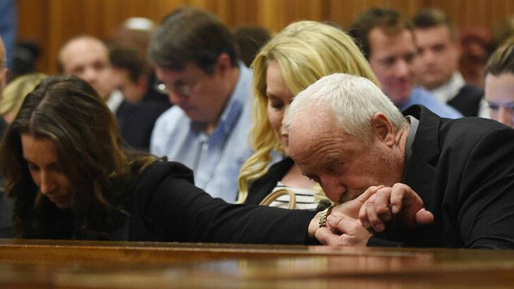 Oscar Pistorius's father Henke Pistorius kisses the hand of his daughter Aimee Pistorius while part of the judgment is handed down in the Pretoria High Court. 