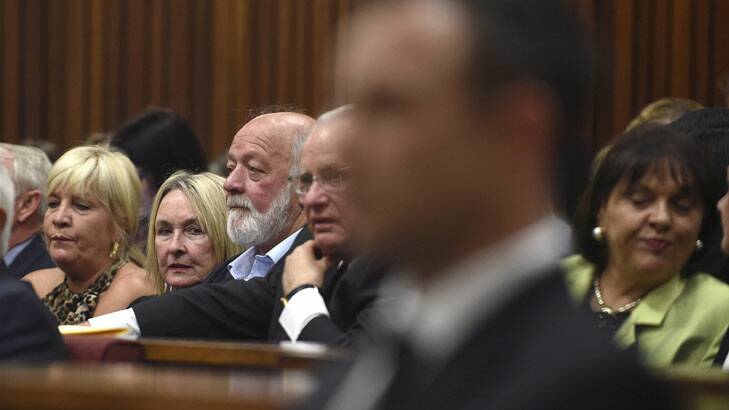 Parents of the late Reeva Steenkamp, Barry and June Steenkamp, second and third from left, behind Oscar Pistorius, foreground, who is in the dock.