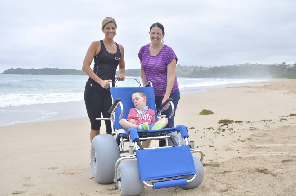 One Fitness 24/7 general manager Nichole Andrews (left) and Lenice Heffernan with Dexter and his new beach wheelchair. Picture: BRENDAN CRABB