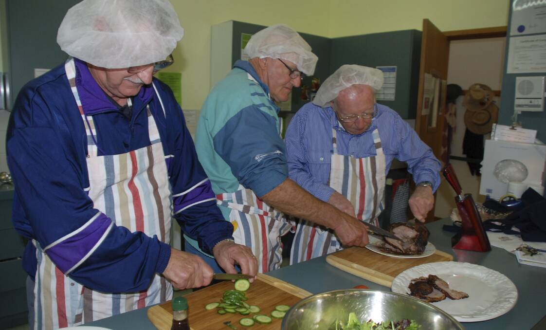 Bill Richardson (left), David Booth and Fred Scales prepare a Christmas-in-July feast for the male carers' cooking group and their partners. Picture: ELIZA WINKLER