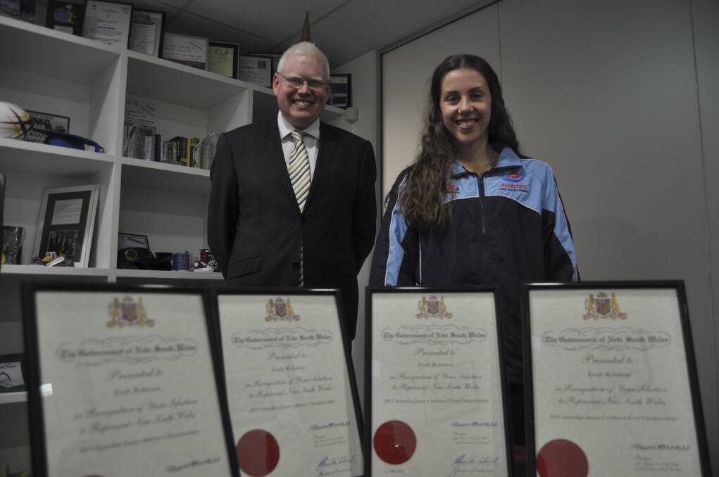 Kiama MP Gareth Ward with Kiama athlete Emily Robinson and the four NSW State Representative Awards she received for her sporting efforts. Picture: PHIL McCARROLL
