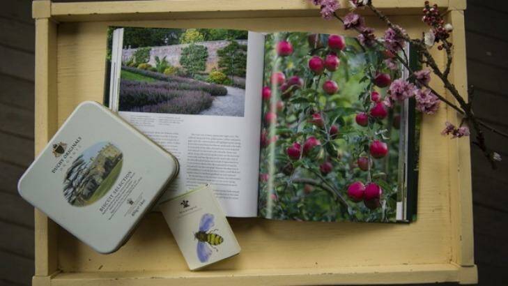 A copy of <i>Highgrove: A Garden Celebrated</i>, some fruit blossom, a tin of Duchy Originals biscuits, and a pack of Highgrove bumblebee cards, photographed on the front verandah at Calthorpes' House. Photo: Rohan Thomson