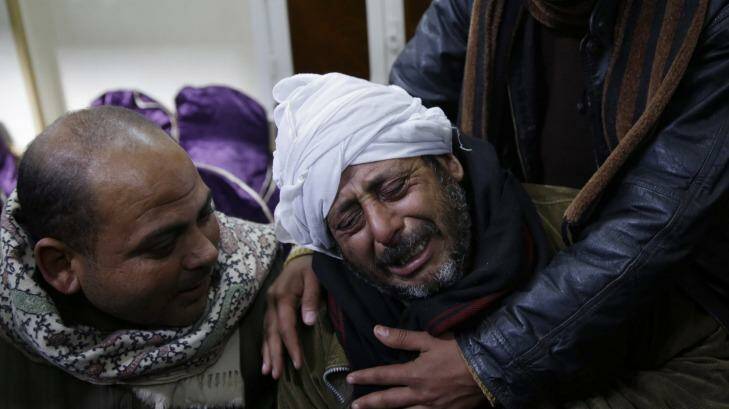 Grief ... A man is comforted by others as he mourns over Egyptian Coptic Christians who were captured in Libya and killed by militants affiliated with the Islamic State group, outside of the Virgin Mary church in the village of el-Aour, near Minya, 220 kilometres south of Cairo, Egypt. Photo: Hassan Ammar