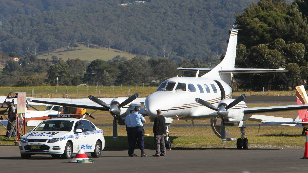 Police and Forensic Services below a Metro 3 twin engine plane at Albion Park airport. Picture Kirk Gilmour