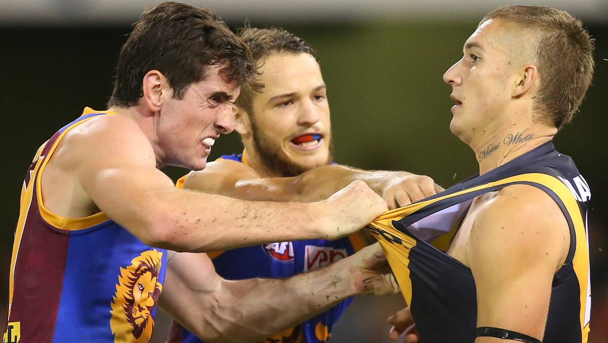 Darcy Gardiner and James Aish of the Lions push Dustin Martin of the Tigers during the round five AFL match between the Brisbane Lions and the Richmond Tigers at The Gabba on April 17, 2014 in Brisbane, Australia. Photo: Chris Hyde/Getty Images.