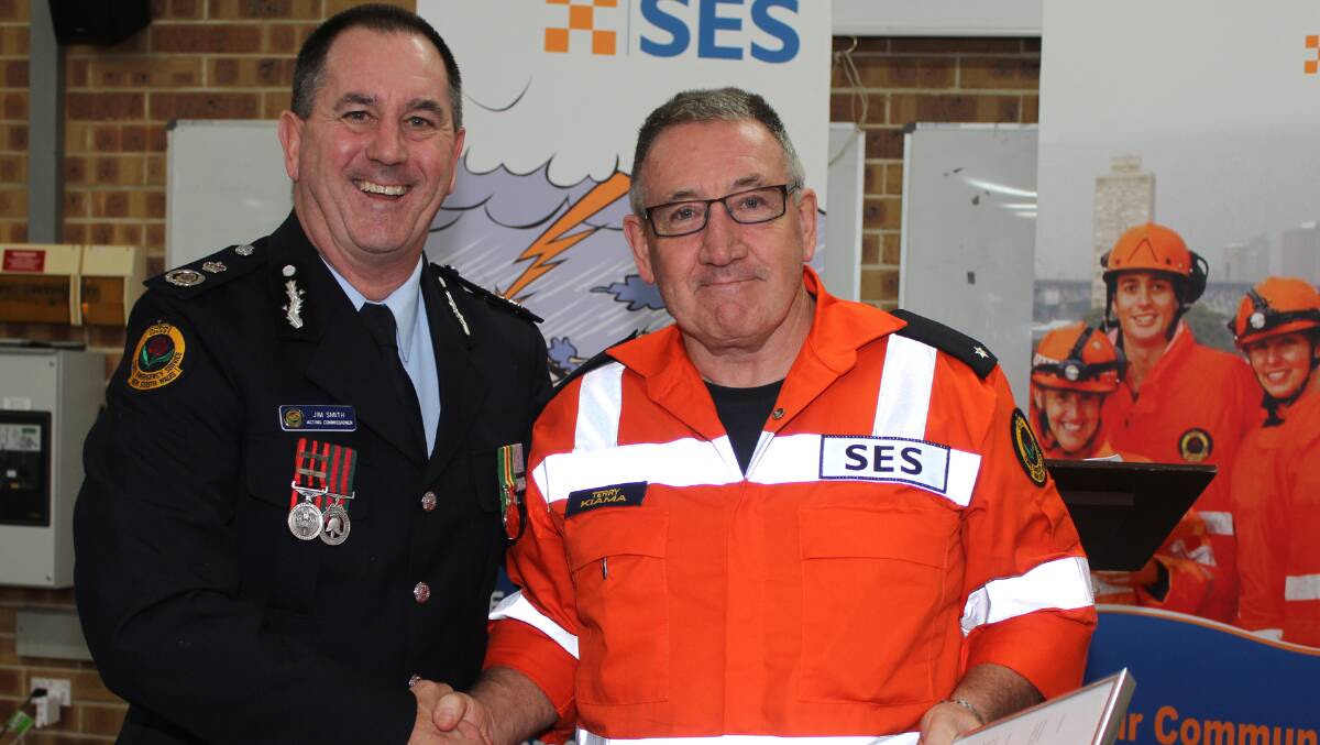 Acting Commissioner of NSW SES, Jim Smith, presents Kiama SES member Terry Beaumont with a special citation certificate on Tuesday night. Piicture: DAVID HALL