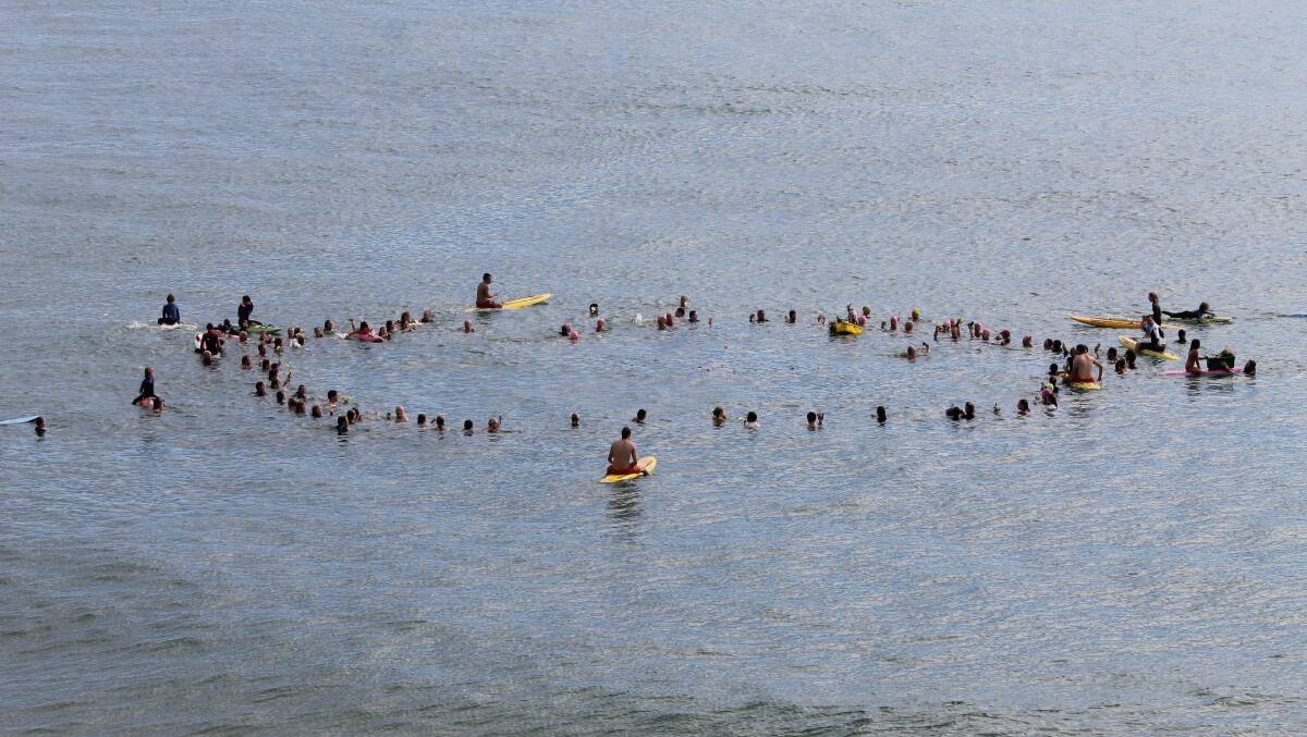 TATHRA: Swimmers thrown flowers in to the water to pay tribute to Christine Armstrong. 