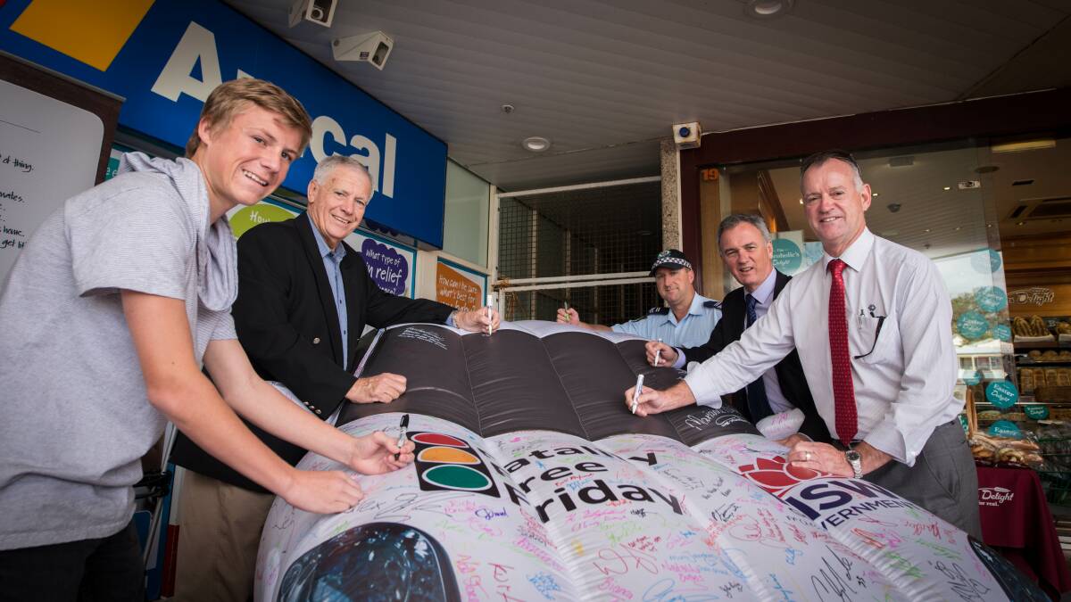 Kiama council staff, students and police signing the inflatable car last year. 