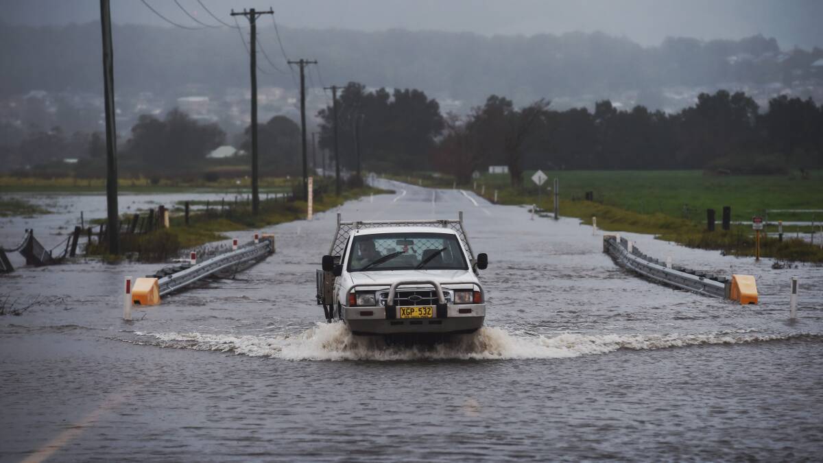 A ute crosses the flooded Illawarra Highway at Albion Park after heavy rainfall across the region. Picture: Nick Moir, SMH