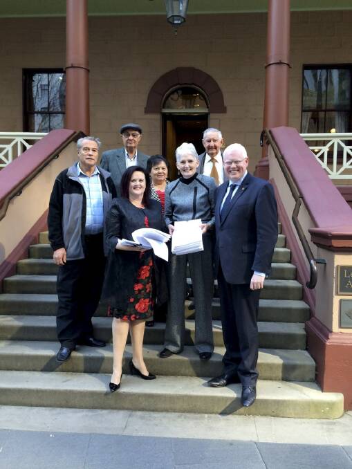 Stop the Hub community members (back) Paul Hockey, Allan Chaseling, Anna Lukies, Harry Lukies and (front) Dianne Quinlin present their 10,000 signature petition at State Parliament to Shellharbour MP Anna Watson (front left) with Kiama MP Gareth Ward (front right) 