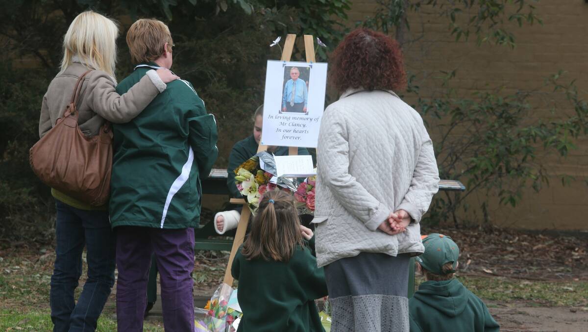Students, parents and former colleagues reflect at a floral tribute for Michael Clancy at Albion Park School on Monday. Picture: ROBERT PEET 