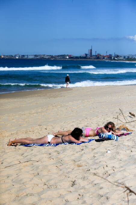 Sophie Wallace and her American friend Madi Ambos enjoy Monday's sunshine at City beach in Wollongong. The late-winter warmth should hang around until a cool change hits on Friday. Picture: Adam McLean