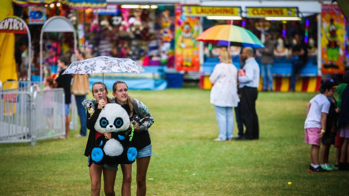 Gerringong's Keeley Doherty and Zoe Cook shelter their prize bear from Friday's rain. Picture: DYLAN ROBINSON