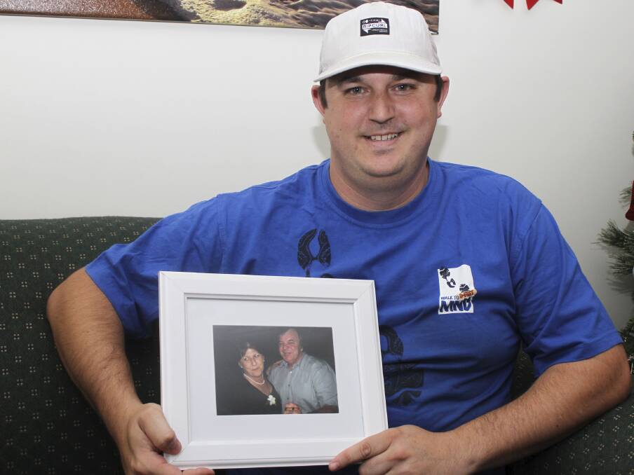 Adam Regal holding a much-loved photo of his mother Sue and late father Steve. His family will again be taking part in the annual Walk To D-feet MND on March 2. Picture: DAVID HALL