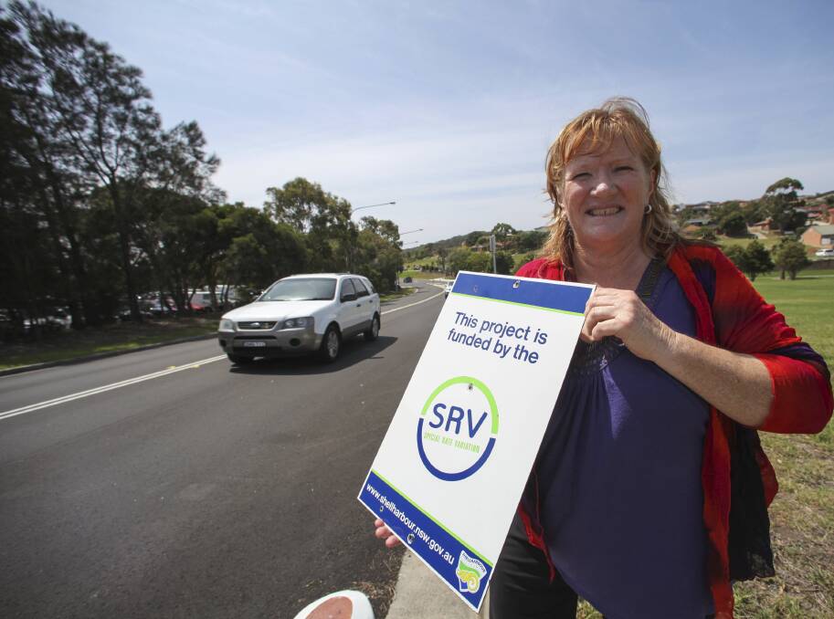Shellharbour Mayor Marianne Saliba holds one of the special rate variation signs at Benson Avenue, where renewal works have taken place in recent months. Picture: DANIELLE CETINSKI
