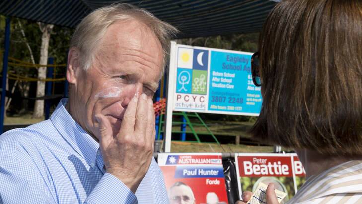 Peter Beattie gets some help with his sunscreen from his wife Heather as he campaigns at Eagleby State School on Saturday morning. Photo: Harrison Saragossi