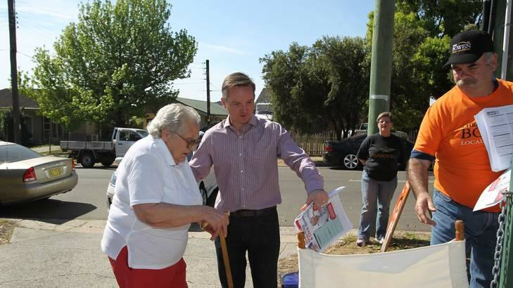 The member for McMahon and Treasurer Chris Bowen helps an elderly voter at the Smithfield Primary School polling booth on Saturday morning. Photo: Marco Del Grande