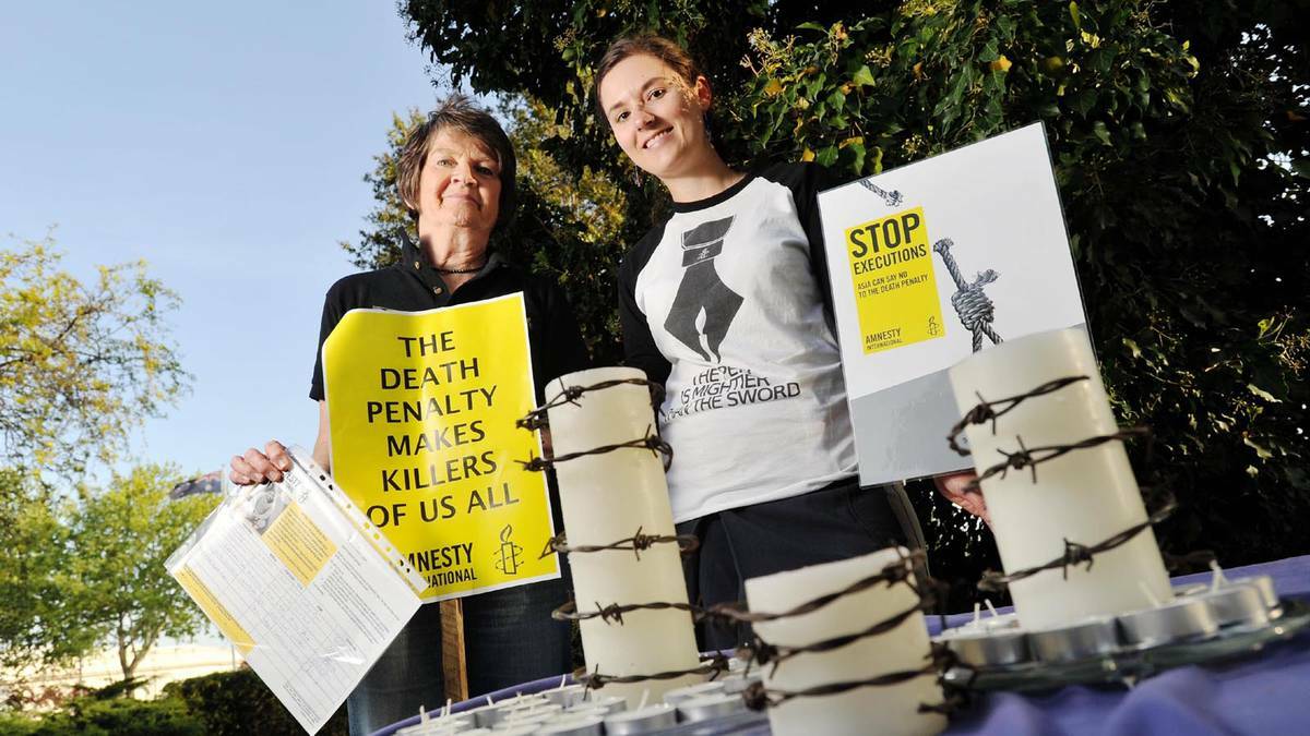 Convener of the Wagga branch of Amnesty International, Gabrielle Robinson (left) and event organiser Holly Wright battled the windy weather for a candlelight vigil in the Victory Memorial Gardens. PHOTO: Alastair Brook/The Daily Advertiser