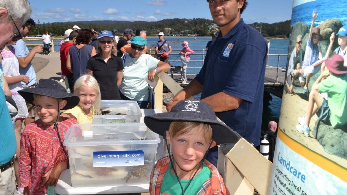  NAROOMA: Local Narooma kids Milo Van Zyl, Jade Wilson and Max Van Zyl find out about life under the wharf with the help of Batemans Marine Park cadet ranger Zac Noel-Stranger.