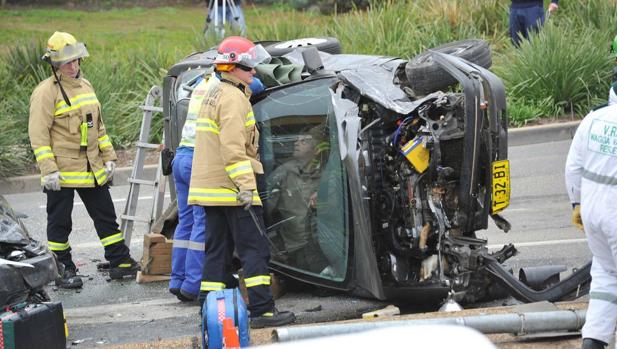  Fire and Rescue NSW personnel talk to a trapped driver whose car collided with a truck, traffic light and a parked car in Wagga. Picture: Michael Frogley