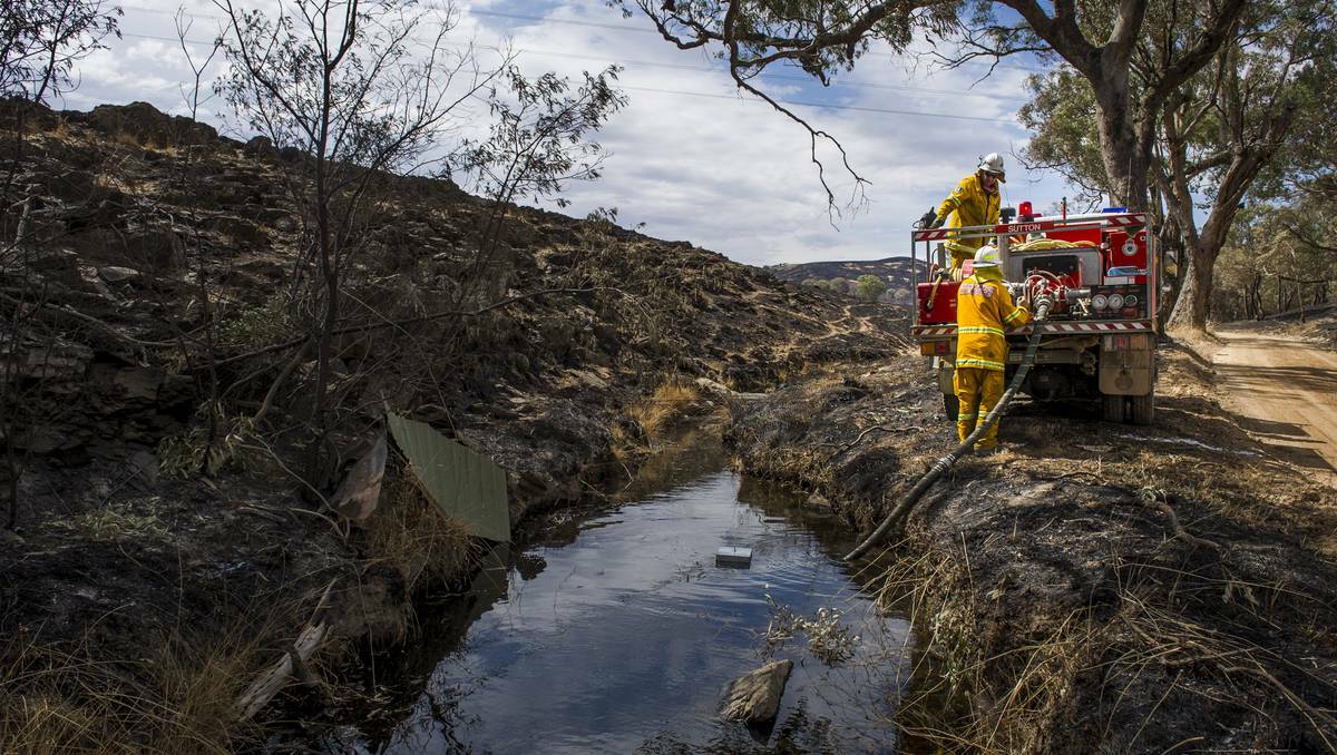 Members of the Sutton RFS, Michael Gardiner and Nick McGlocklin, fill up their truck from a creek next to Woolgarlo Rd, near Yass on January 12, 2013. Photo: Rohan Thomson/The Canberra Times