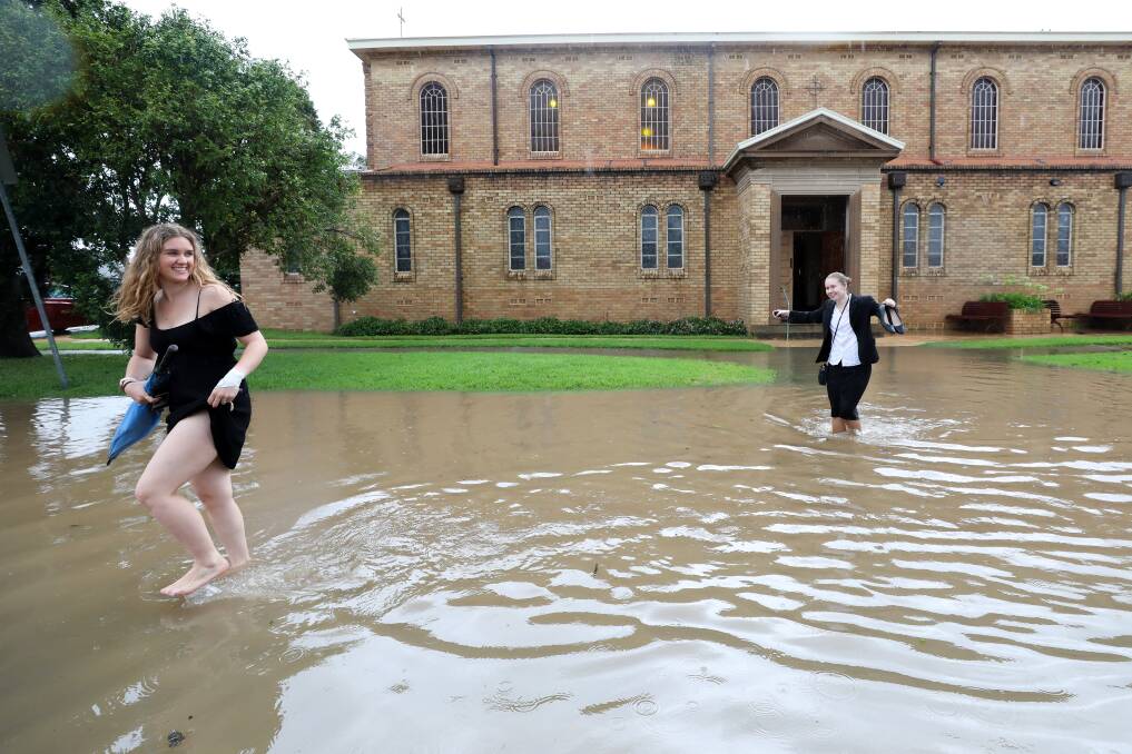 February 9. Two women return to their cars on Grace Street in Unanderra after attending a funeral at the Immaculate Conception Catholic Church in the aftermath of a severe weather event that hit the Illawarra brining flash flooding across the region.