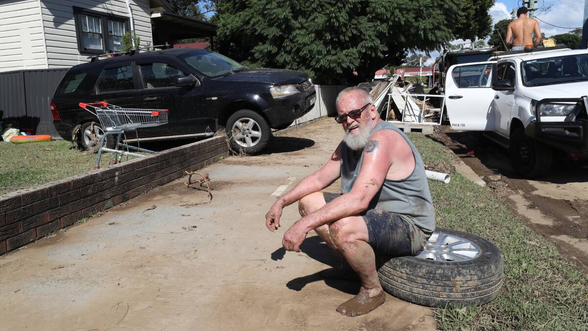 Jeff Jordan takes a breather from cleaning up after the flood that ripped down Arrow Avenue at Figtree. Picture by Robert Peet