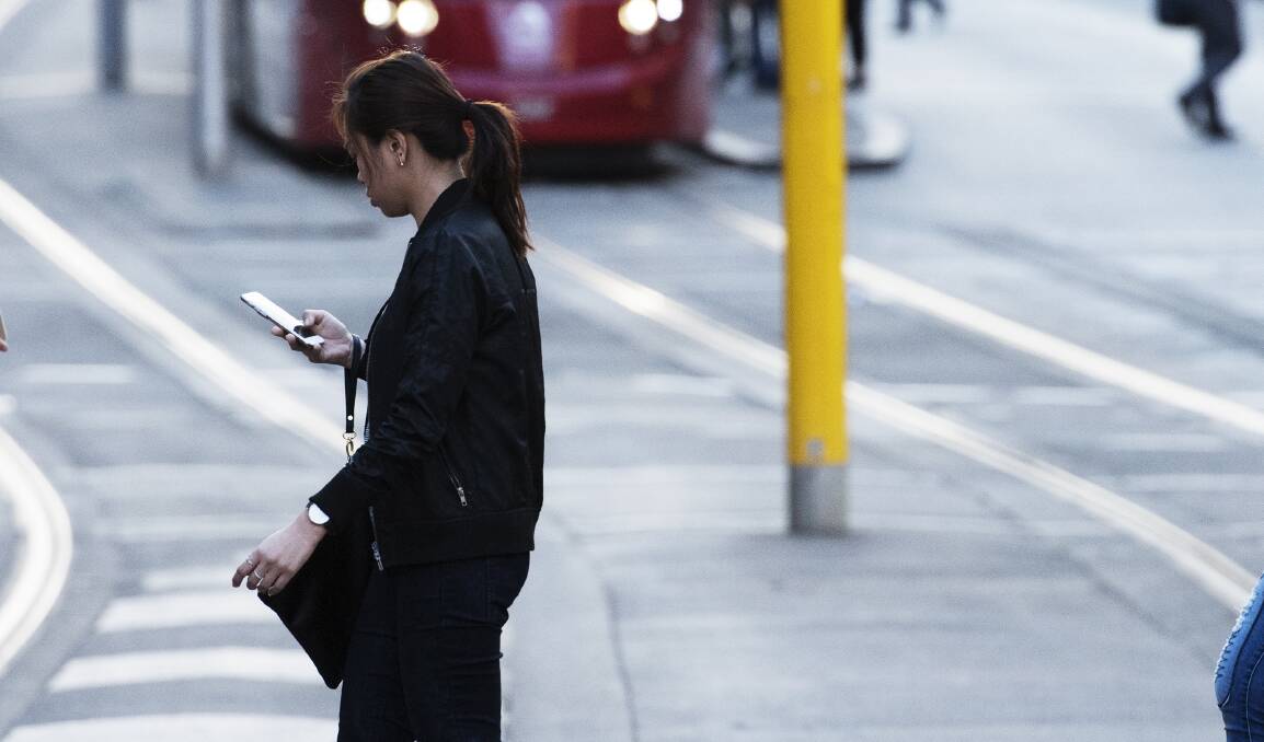 An NRMA study found that 36 per cent of pedestrians crossed the road while distracted by their smartphone or wearing earphones. Photo: James Brickwood