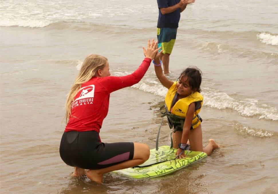 Christian surfers helper with new migrant at a Surf Together day in the past