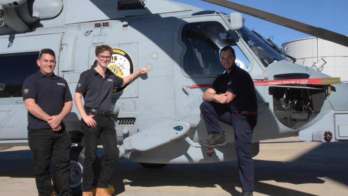 New Sikorsky Australia apprentices Joel Grimston, Nicholas Poelczer and Luca Taglieri with a Royal Australian Navy MH-60R (Romeo) maritime helicopter they will son be working on.