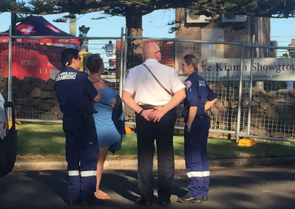A woman who was rescued from Kiama Surf Beach, waiting with paramedics for her clothes to be retrieved from the Red Hot Summer Festival which she had been attending.