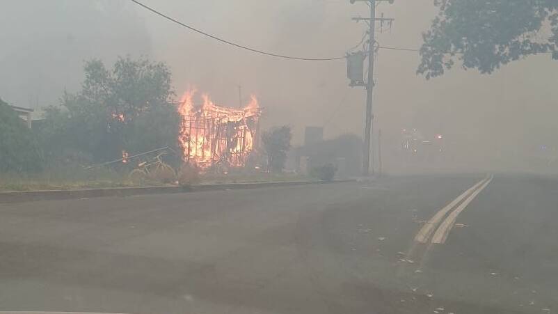 A house beside Batlow's service station goes up in flames on Saturday. Both were destroyed. Picture: Matthew Rudd