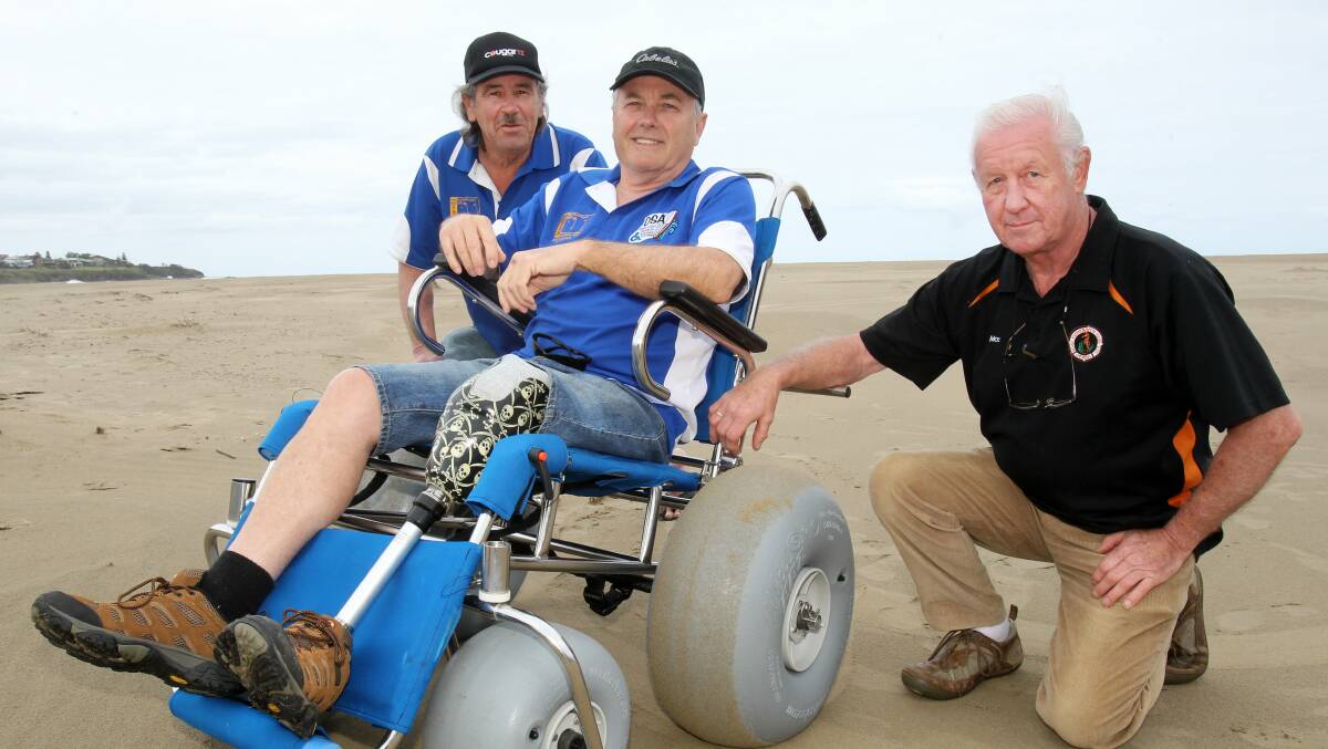 Ian McDermott from Gerroa Boat Fisherman’s Club pushes James Smith from the Disabled Surfers' Association on the new wheelchair at Seven Mile Beach. Pictured in the middle is Cecil Campbell from the DSA. Picture: GREG TOTMAN